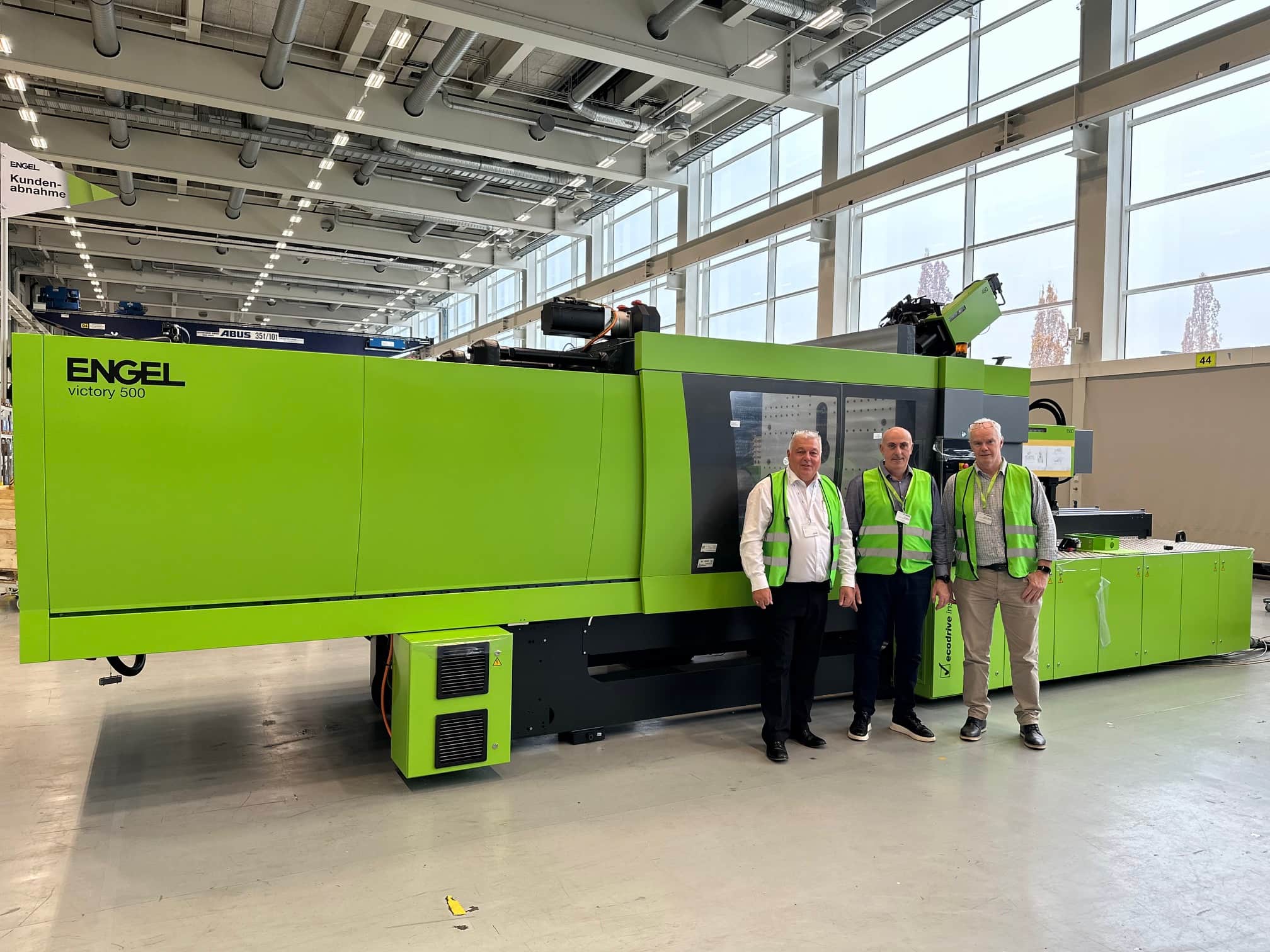 ENGEL injection moulding machine with team celebrating long-term manufacturing milestone